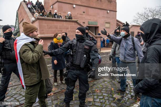 Police officer stands between left wing conter demonstrators and opponents of what they claim are restrictions to their personal freedoms due to...