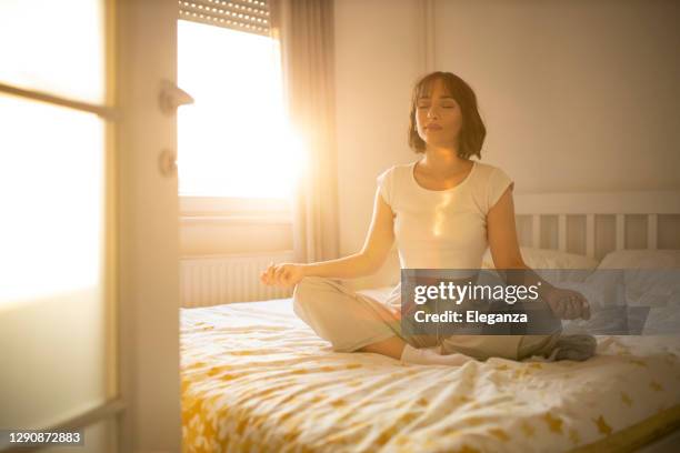 mooie vrouw die in haar bed wordt wakker, zij praktizert yoga. jonge mooie vrouw die in haar bed volledig uitgerust wordt wakker. vrouw die yoga in bed na wakker maakt uitoefent. - home sweet home stockfoto's en -beelden