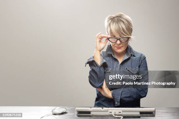 businesswoman sitting at desk holding eyeglasses - suspicion office stock pictures, royalty-free photos & images