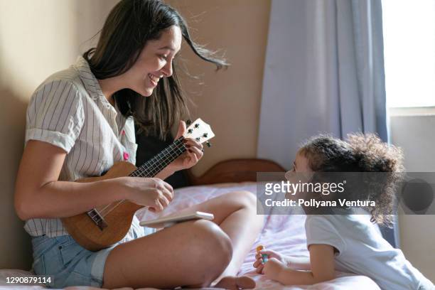 aunt playing ukulele for niece - niece stock pictures, royalty-free photos & images