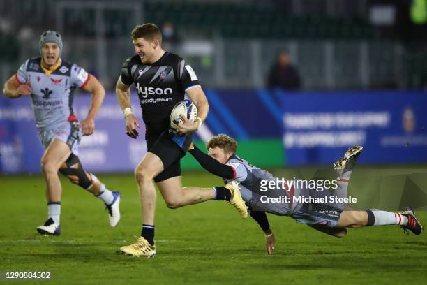 Ruaridh McConnochie of Bath evades the challenge of Angus O'Brien of Scarlets during the Heineken Champions Cup Pool 1 match between Bath Rugby and...