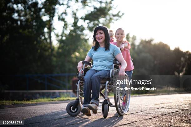 mère dans le fauteuil roulant et sa fille passant le temps ensemble en stationnement - paraplegic woman photos et images de collection