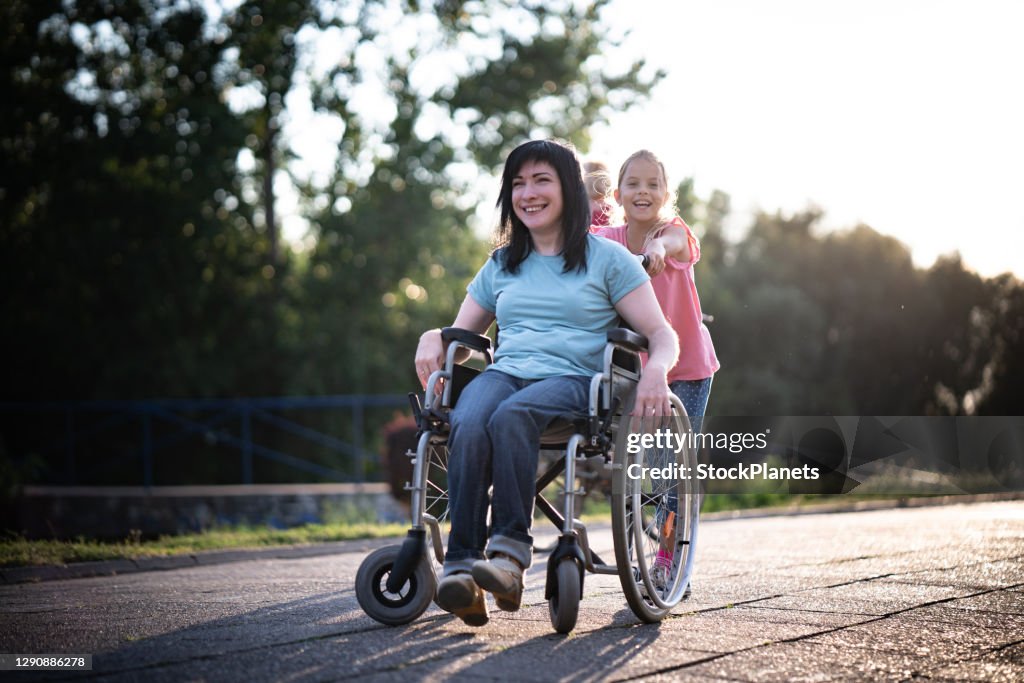 Mother in wheelchair and her daughter spending time together in park