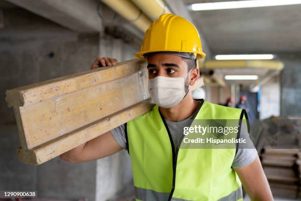 entrepreneur utilisant un masque facial tout en travaillant à un chantier de construction portant le bois - masque respiratoire photos et images de collection