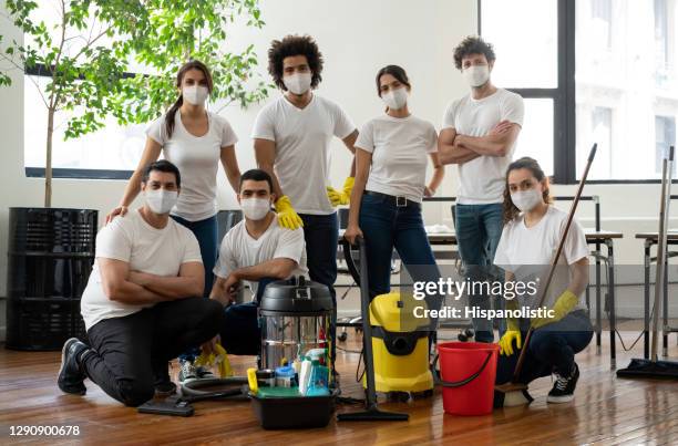 group of professional cleaners working at an office wearing facemasks during the pandemic - cleaning crew stock pictures, royalty-free photos & images