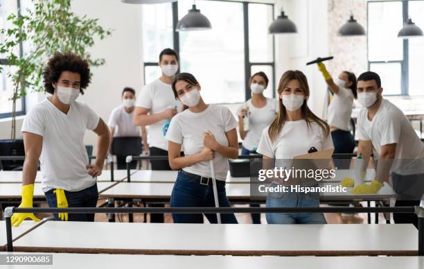 group of professional cleaners working at an office wearing facemasks during the pandemic - cleaning crew stock pictures, royalty-free photos & images