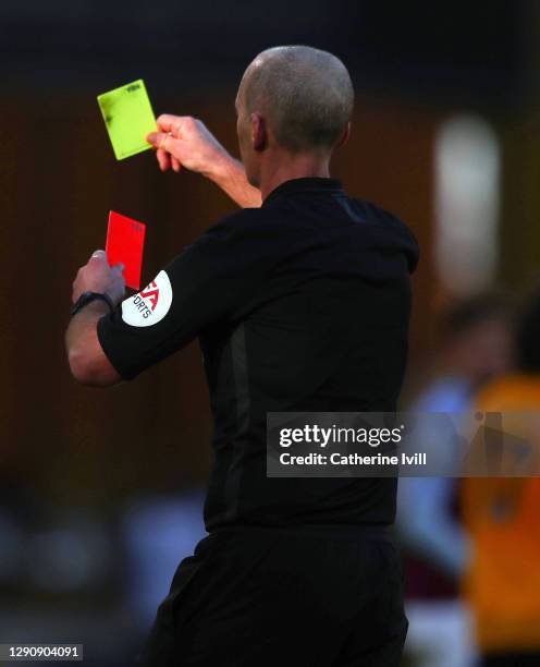 Referee Mike Dean holds a red and yellow card during the Premier League match between Wolverhampton Wanderers and Aston Villa at Molineux on December...