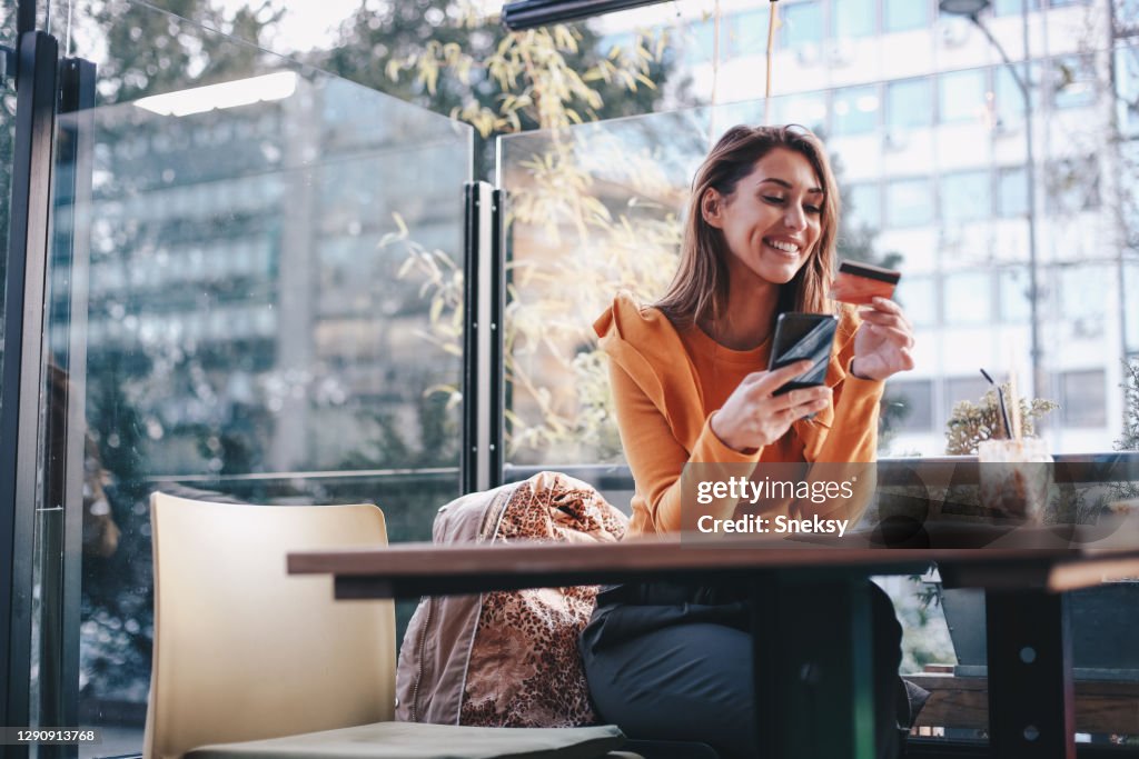 Junge Frau kauft online, mit ihrem Handy. COVID-19 Konzept.