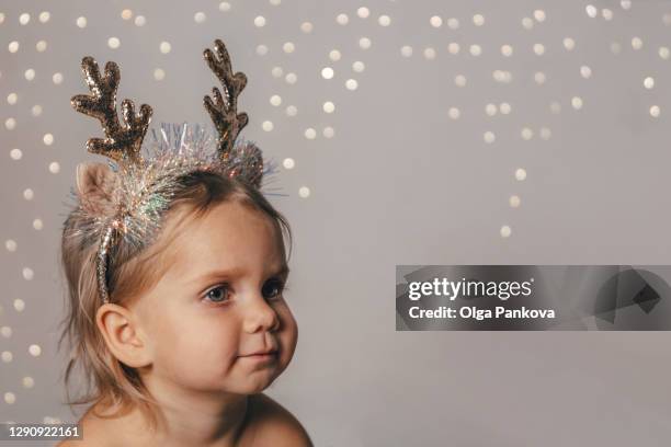 a child wearing reindeer horns. christmas and new year's concept. beige gray background. - reindeer horns stock pictures, royalty-free photos & images