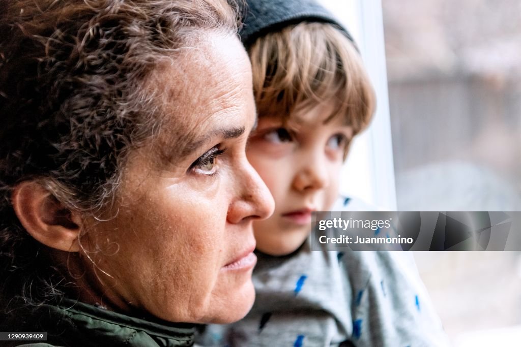 Reife Frau posiert mit ihrem Sohn, sehr traurig Blick durch das Fenster besorgt über den Verlust ihres Jobs durch Covid-19 Pandemie