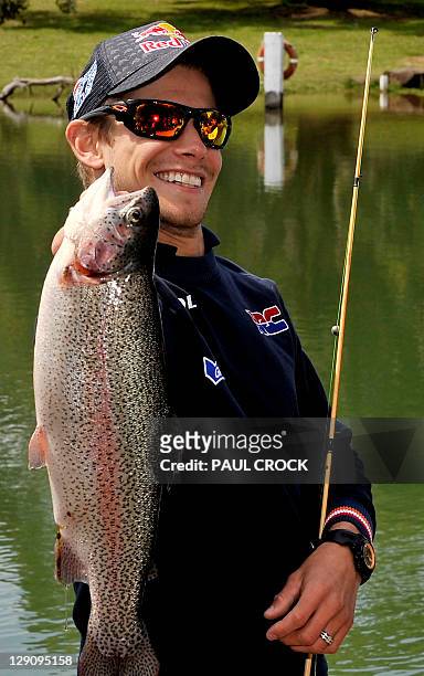 Honda rider Casey Stoner of Australia holds up a fish he caught at the Phillip Island Trout Farm during a media preview for the Australian Grand Prix...