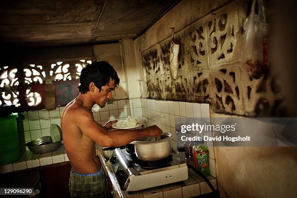 James Gumban from The Ambassadors of Goodwill, a group of ex-prisoners dancing, pours himself a portion of lunch in a shared hourse of some of the...