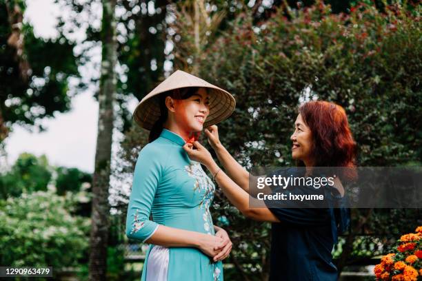 senior woman dressing her daughter in traditional vietnamese clothing - vietnamese ethnicity stock pictures, royalty-free photos & images