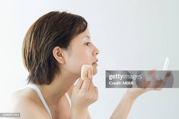 woman putting on foundation - powder compact 個照片及圖片檔