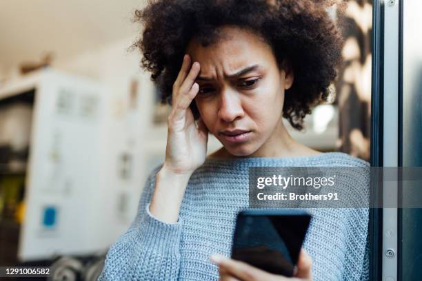 young african american woman reading bad news on her mobile device - damaged phone stock pictures, royalty-free photos & images