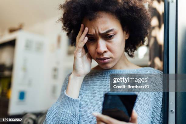 young african american woman reading bad news on her mobile device - female worried mobile imagens e fotografias de stock