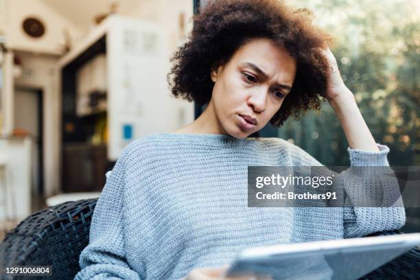 junge afroamerikanische frau liest schlechte nachrichten auf ihrem mobilen gerät - bad news stock-fotos und bilder