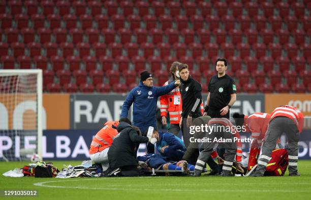 Manuel Baum, Head Coach of FC Schalke 04 checks on Mark Uth of FC Schalke 04 as he receives treatment after a challenge during the Bundesliga match...