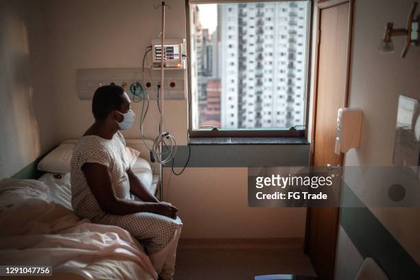 senior patient using mask looking through window at hospital - coronavirus hospital stock pictures, royalty-free photos & images