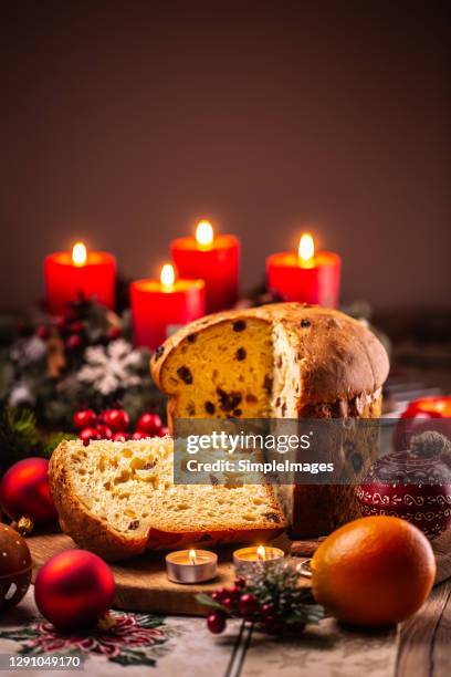 italian sweet festive delicacy panettone fruitcake with a christmas wreath with four candles in the background. - panettone stock-fotos und bilder