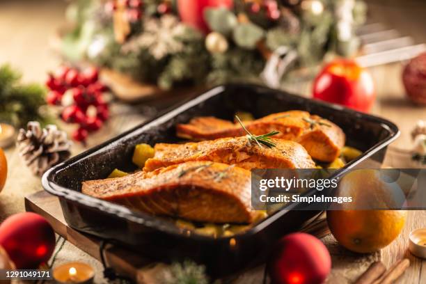 baked festive meal of salmon in a baking tray surrounded by christmas decoration. - zalm gerecht stockfoto's en -beelden