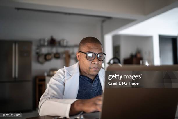 doctor making an online consultation by video chat at home - doctor male laptop stock pictures, royalty-free photos & images