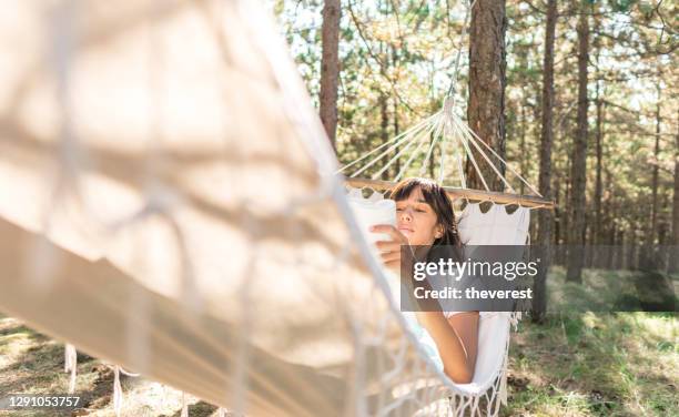 women reading a book in forest hammock - hammock stock pictures, royalty-free photos & images