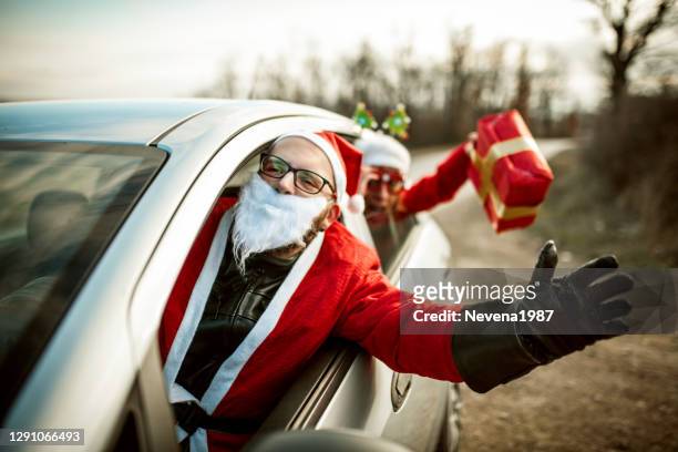 jonge kerstman die een auto drijft en een pret met zijn vrouwelijke vriend heeft - christmas driving stockfoto's en -beelden