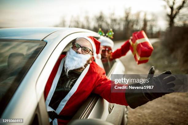 young santa claus driving a car and having a fun with his female friend - christmas driving stock pictures, royalty-free photos & images