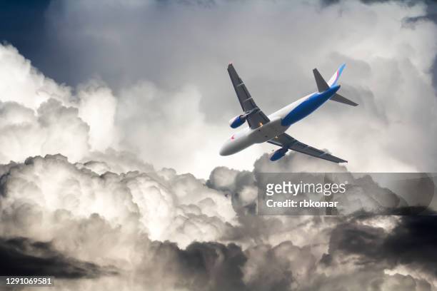 a commercial airplane flies through storm clouds - commercial aircraft flying stockfoto's en -beelden