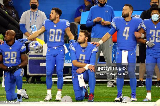 Adrian Peterson and Matthew Stafford of the Detroit Lions kneel during the national anthem before their game against the Green Bay Packers at Ford...