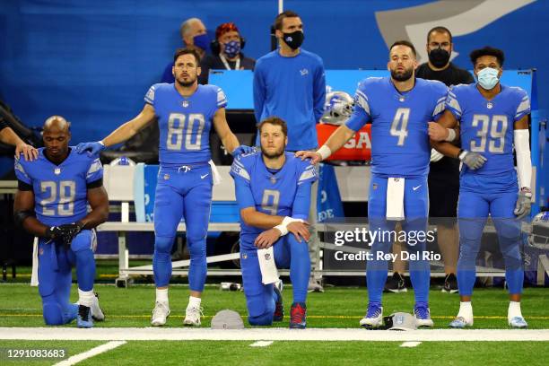 Adrian Peterson and Matthew Stafford of the Detroit Lions kneel during the national anthem before their game against the Green Bay Packers at Ford...