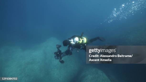 scuba diver descends into the sea with film and sound equipment - underwater film camera - fotografias e filmes do acervo