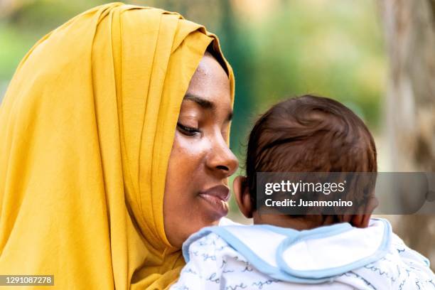 muslim mother holding her baby - refugee babies stock pictures, royalty-free photos & images
