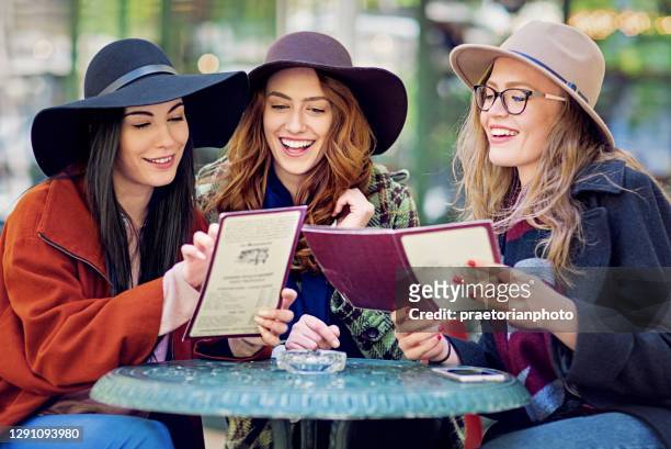 girlfriends are looking in a menus at cafeteria - menu specials stock pictures, royalty-free photos & images