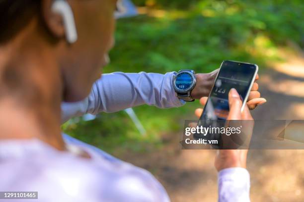 vista sobre el hombro en la mujer usando el software de seguimiento - reloj inteligente fotografías e imágenes de stock