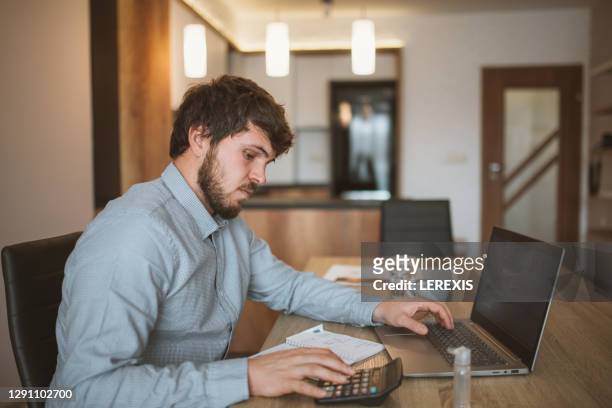 young businessman working at home with laptop - filing documents stock pictures, royalty-free photos & images