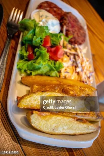 hamburguesas de quinoa y semillas, con papas asadas, ensalada fresca y aderezo de queso de pepino y menta (comida vegetariana). - comida vegetariana stockfoto's en -beelden