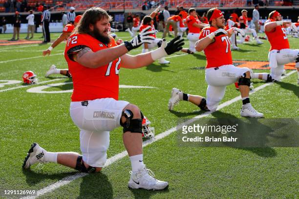 Left guard Josh Sills and right guard Hunter Woodard, and center Ry Schneider of the Oklahoma State Cowboys stretch before a game against the Texas...