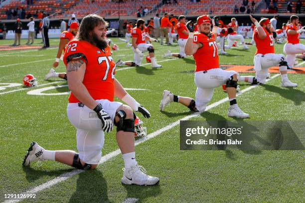 Left guard Josh Sills and right guard Hunter Woodard, and center Ry Schneider of the Oklahoma State Cowboys stretch before a game against the Texas...