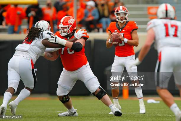 Quarterback Spencer Sanders of the Oklahoma State Cowboys looks for an open receiver with a block by left guard Josh Sills against the Texas Tech Red...