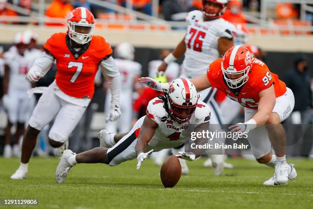 Running back SaRodorick Thompson of the Texas Tech Red Raiders dives on his own fumble on a nine-yard gain against defensive end Kody Walterscheid of...