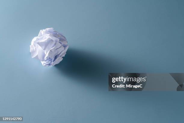 a crumpled paper ball on blue - zerdrückt stock-fotos und bilder