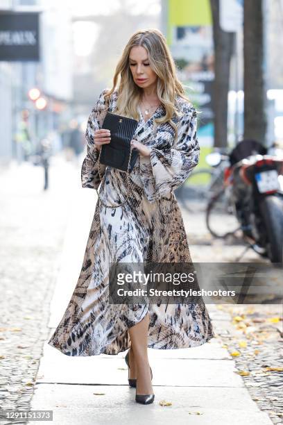 German actress Xenia Seeberg wearing a long brown and beige colored snake print dress by Fate Kastrati, a black bag with gold details by Chanel and...