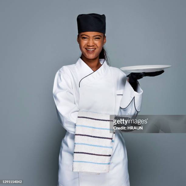 happy female chef holding napkin and empty plate - chef portrait stock pictures, royalty-free photos & images