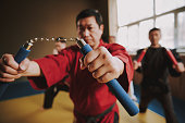Martial arts fighters in different colors keikogi training with nunchuck.