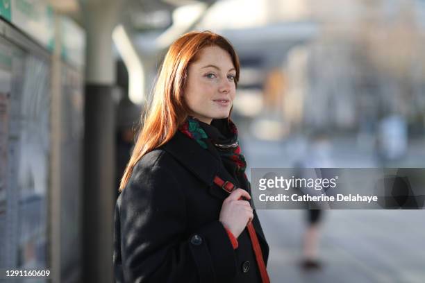 a beautiful young redhead woman waiting the tram in paris - portrait français photos et images de collection