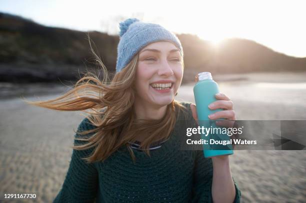 beautiful carefree woman on winter beach with green flask. - dougal waters 個照片及圖片檔