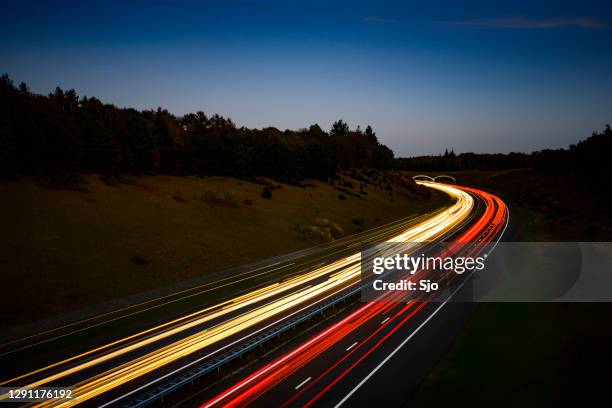 luci del traffico che passano su un'autostrada di notte - pedaggio foto e immagini stock