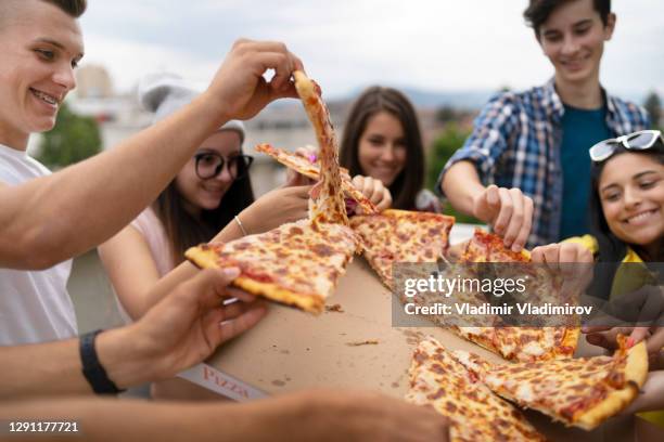 happy students eating pizza together on a party - pizza party stock pictures, royalty-free photos & images